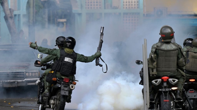 Membros do esquadrão de choque da Guarda Nacional Bolivariana (GNB) circulam em meio a gás lacrimogêneo no bairro de Chacao, enquanto opositores do presidente venezuelano Nicolas Maduro participam de uma manifestação, em Caracas, em 30 de julho de 2024. Quatro pessoas morreram e dezenas ficaram feridas quando as autoridades interromperam os protestos contra a reivindicação de vitória do presidente Nicolas Maduro nas eleições do país no fim de semana.(YURI CORTEZ/AFP via Getty Images)