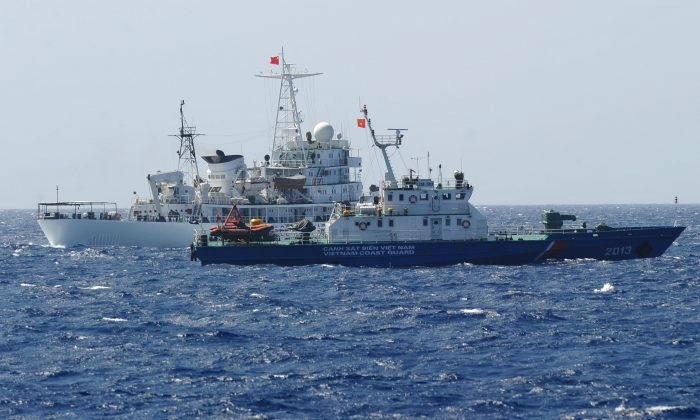 Um navio da guarda costeira chinesa (atrás) navegando ao lado de um navio da guarda costeira vietnamita (frente), perto da plataforma de perfuração de petróleo da China em águas disputadas no Mar da China Meridional, em 14 de maio de 2014. (Hoang Dinh Nam/AFP/Getty Images)
