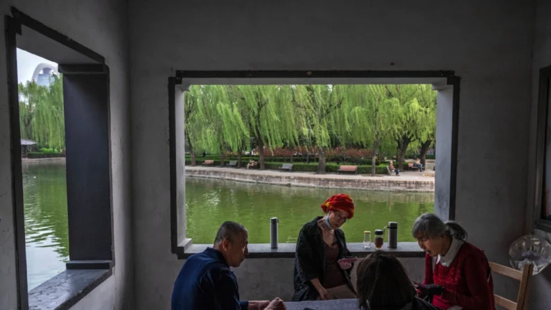 Pessoas jogam cartas em um parque local em Pequim em 18 de abril de 2024 (Kevin Frayer/Getty Images)
