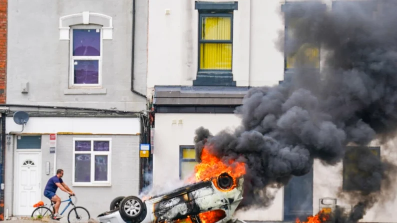 Um carro pega fogo após ser capotado durante um protesto anti-imigração em Middlesbrough, Inglaterra, em 4 de agosto de 2024. (Owen Humphreys/PA)
