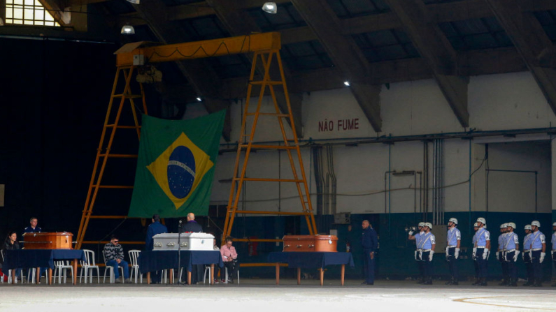 Parentes das vítimas do acidente aéreo da Voepass são vistos ao lado de seus caixões durante uma missa na base aérea de São Paulo em Guarulhos, Brasil, em 13 de agosto de 2024 (Foto de MIGUEL SCHINCARIOL/AFP via Getty Images)