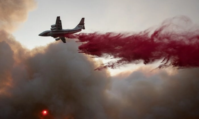 O sol é visto através de uma nuvem de fumaça enquanto um avião lança retardante de fogo vermelho no Glass Fire em Deer Park, Califórnia, em 27 de setembro de 2020. (Adrees Latif/Reuters)
