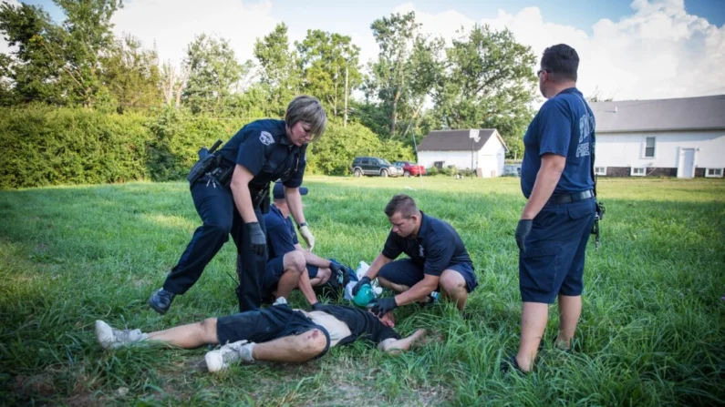 A polícia local e os paramédicos ajudam um homem que está tendo uma overdose no bairro Drexel de Dayton, Ohio, em 3 de agosto de 2017. (Epoch Times)
