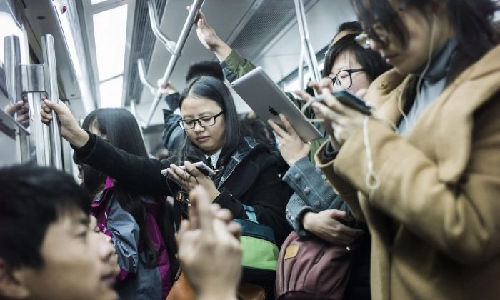 Passageiros assistem a filmes em seus celulares e tablets em um vagão do metrô em Pequim em 17 de novembro de 2014 (Fred Dufour/AFP/Getty Images)