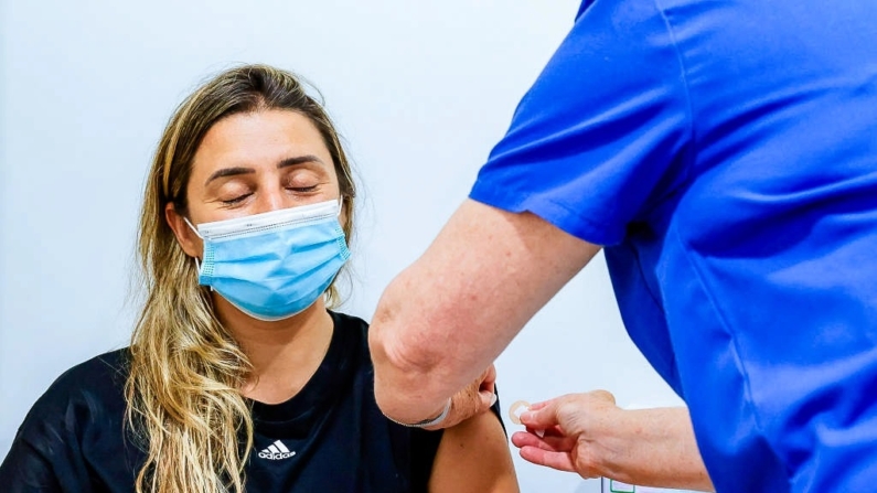 Uma mulher fecha os olhos enquanto recebe uma vacina contra COVID-19 no Sydney Road Family Medical Practice em Balgowlah, em Sydney, Austrália, em 10 de janeiro de 2022 (Jenny Evans/Getty Images)