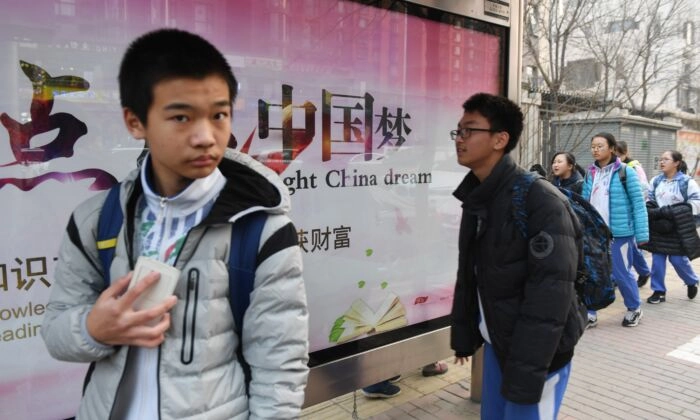 Jovens passam por um outdoor de propaganda sobre o "Sonho Chinês", um slogan associado ao líder chinês Xi Jinping, do lado de fora de uma escola em Pequim, em 12 de março de 2018. Greg Baker/AFP via Getty Images
