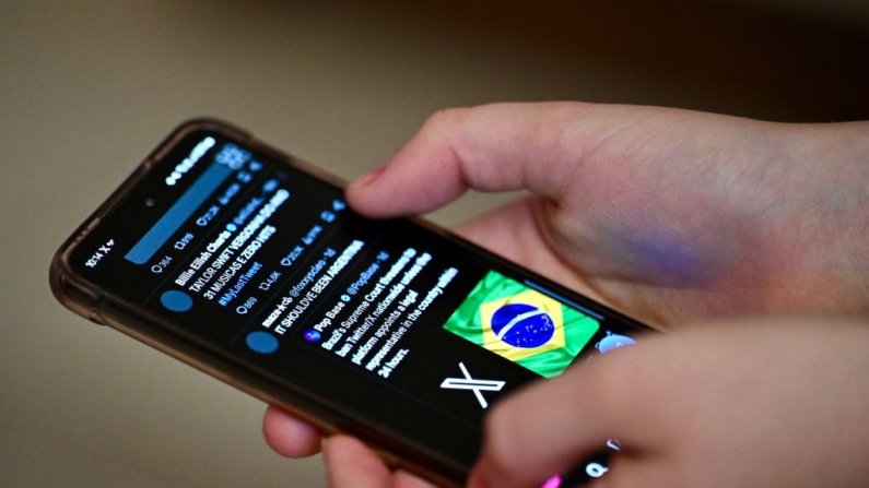 Um usuário brasileiro da rede social X, antigo Twitter, navega por publicações em um telefone celular em Brasília, em 31 de agosto de 2024. Apesar da ordem judicial para bloquear o X em todo o Brasil, emitida pelo juiz do Supremo Tribunal Federal Alexandre de Moraes, alguns usuários ainda conseguem acessar as páginas da rede social no país (Foto de EVARISTO SA/AFP via Getty Images)