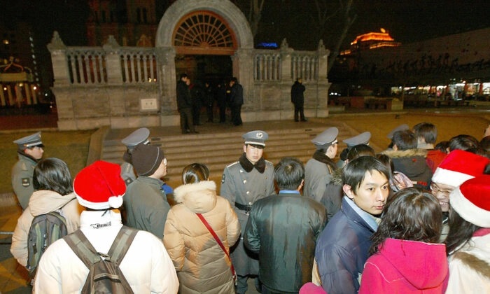 Guardas de segurança chineses juntamente com a polícia mantém centenas de fiéis cristãos chineses longe da Igreja Católica de Wangfujing durante a missa de Natal em Pequim, em 25 de dezembro de 2003, nesta foto de arquivo (Goh Chai Hin/AFP via Getty Images)