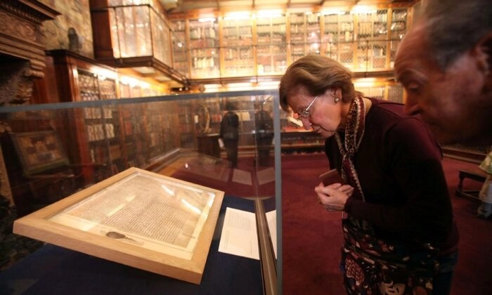 Os visitantes examinam um dos primeiros manuscritos originais da Carta Magna de 1217 na Biblioteca e Museu Morgan em 21 de abril de 2010, na cidade de Nova Iorque (Mário Tama/Getty Images)