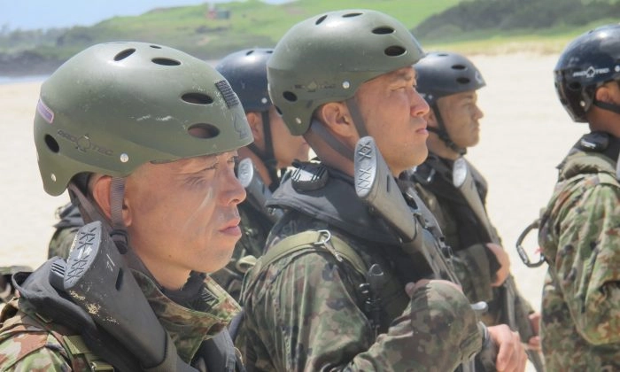 Soldados japoneses em uma equipe de reconhecimento em posição de sentido na praia da Baía de Kaneohe, Havaí, após prática de desembarque anfíbio na terça-feira, 29 de julho de 2014. Os exercícios de desembarque anfíbio, que são relativamente novos para o exército japonês, ocorrem enquanto Tóquio tenta aumentar sua capacidade de defender pequenas ilhas que controla, mas que a China reivindica como suas. AP Photo/Audrey McAvoy
