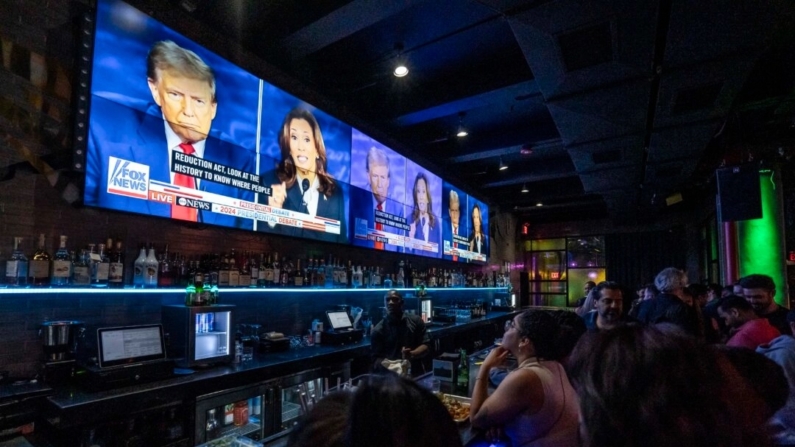 As pessoas assistem ao debate presidencial entre a candidata presidencial democrata, a vice-presidente Kamala Harris, e o candidato presidencial republicano, o ex-presidente Donald Trump, em uma festa no bar e lounge Slate na cidade de Nova York em 10 de setembro de 2024 (Samira Bouaou/The Epoch Times)