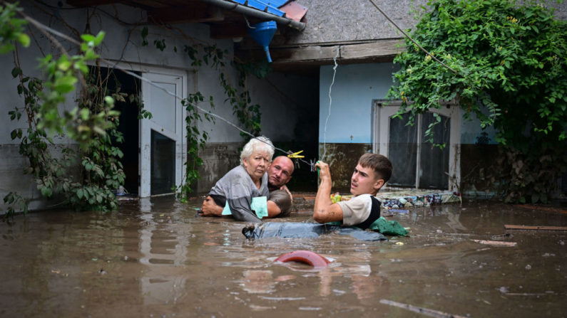 Moradores locais resgatam uma idosa das águas da enchente no vilarejo romeno de Slobozia Conachi em 14 de setembro de 2024. A tempestade Boris matou quatro pessoas na Romênia em 14 de setembro de 2024, quando chuvas excepcionais causaram inundações em vários países da Europa Central e Oriental. Os serviços de resgate da Romênia anunciaram que encontraram os corpos de quatro pessoas durante uma operação de busca na região mais atingida, Galati (sudeste), onde 5.000 casas foram afetadas(Foto de DANIEL MIHAILESCU/AFP via Getty Images)