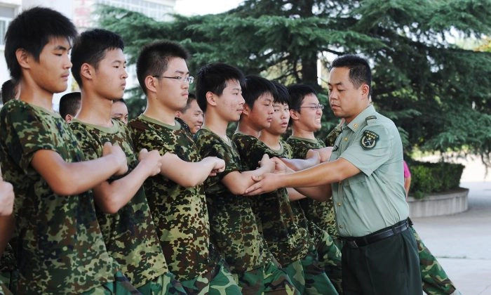 Estudantes praticam marcha sob a supervisão de um soldado do Exército de Libertação Popular durante a primeira semana do serviço militar do ensino médio em uma base em Hefei, província de Anhui, leste da China, em 5 de agosto de 2010. Imagens AFP/Getty
