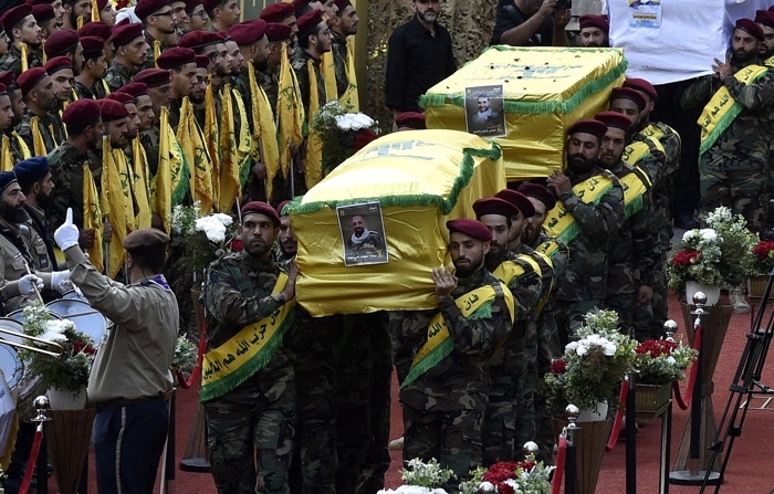 Combatentes do Hezbollah carregam os caixões de quatro pessoas mortas um dia antes em explosões de pagers, durante um cortejo fúnebre no subúrbio sul de Beirute, no Líbano, em 18 de setembro de 2024 (EFE/EPA/WAEL HAMZEH)