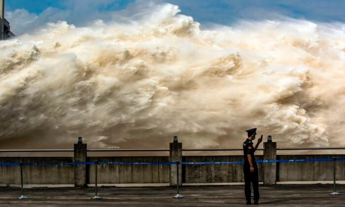 Um guarda de segurança olha seu smartphone enquanto a água é liberada da Barragem das Três Gargantas, um gigantesco projeto hidrelétrico no rio Yangtze, para aliviar a pressão das enchentes em Yichang, província de Hubei, no centro da China, em 19 de julho de 2020. STR/AFP via Getty Images
