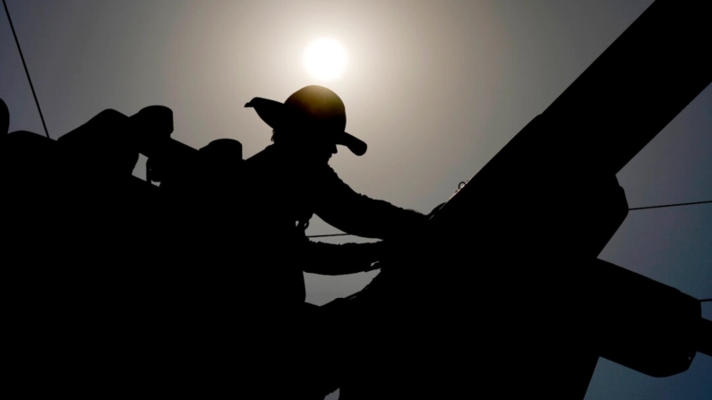 Um eletricista trabalha em linhas elétricas sob o sol da manhã, em Phoenix, em 12 de julho de 2024. (Matt York/AP Photo)