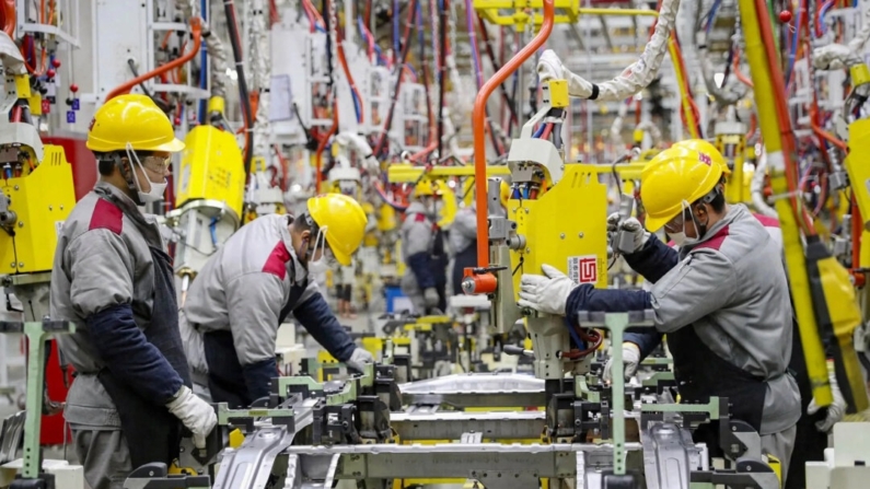 Funcionários trabalhando em uma linha de montagem de carros em uma fábrica automotiva de Pequim em Qingdao, na província de Shandong, no leste da China, em 14 de janeiro de 2023. (STR/AFP via Getty Images)