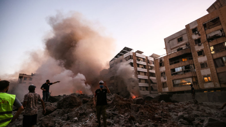 Pessoas e equipes de resgate em meio aos escombros de um prédio destruído em um ataque aéreo israelense no bairro de Haret Hreik, nos subúrbios ao sul de Beirute, em 27 de setembro de 2024. Uma fonte próxima ao Hezbollah disse que os ataques israelenses em massa nos subúrbios ao sul de Beirute destruíram seis prédios. (IBRAHIM AMRO/AFP via Getty Images)