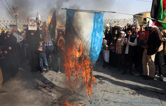 Pessoas queimam uma bandeira israelense enquanto se reúnem para uma manifestação anti-Israel após um ataque com mísseis realizado pelo Irã contra Israel na noite anterior, na Praça Imam Hussein, em Teerã (EFE/EPA/ABEDIN TAHERKENAREH)