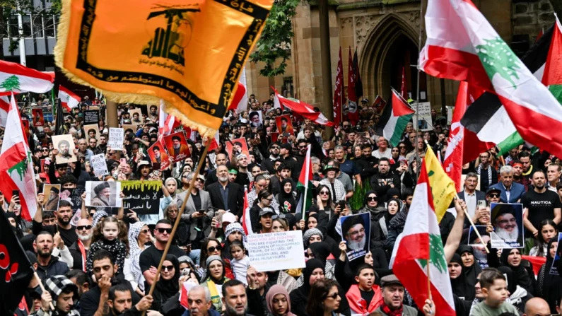 Centenas de manifestantes seguram bandeiras e fotos de Hassan Nasrallah, falecido líder do grupo libanês Hezbollah, em uma manifestação de protesto no distrito comercial central de Sydney, Austrália, em 29 de setembro de 2024. (Saeed Khan/AFP via Getty Images)