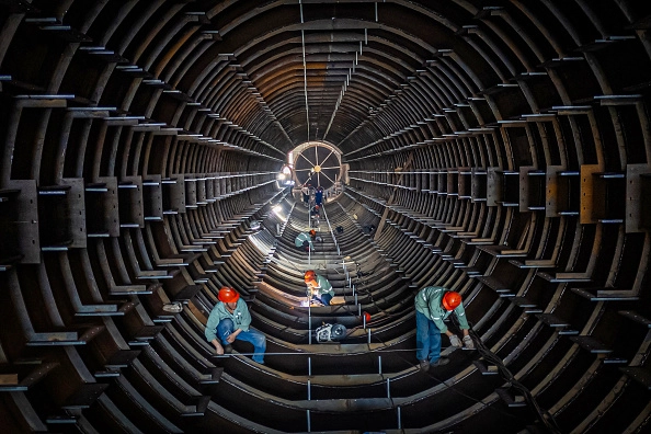 Funcionários trabalham em uma linha de produção de torres de tubos de aço em uma fábrica em Haian, na província de Jiangsu, no leste da China, em 1º de setembro de 2024. STR/AFP via Getty Images
