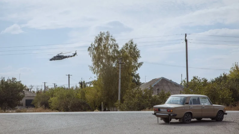 Um helicóptero militar ucraniano voa enquanto um carro dirige em uma estrada em meio à invasão russa, na região de Donetsk, Ucrânia, em 4 de outubro de 2024 (Roman Pilipey/AFP via Getty Images)