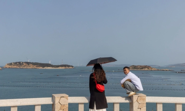 Pessoas em pé em uma plataforma de observação com vista para o Estreito de Taiwan na Ilha de Pingtan, província de Fujian, China, em 10 de abril de 2023. (Thomas Peter/Reuters)