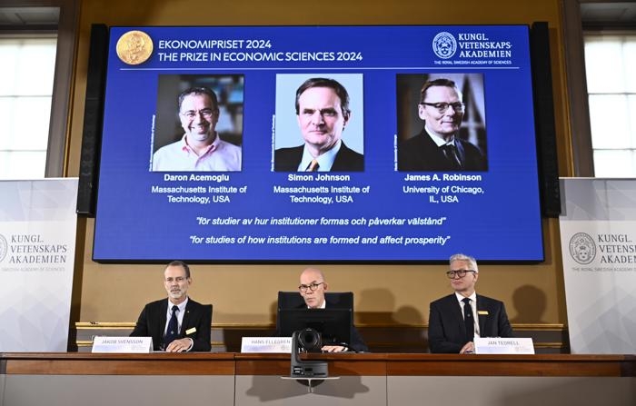 O secretário permanente da Academia de Ciências, Hans Ellegren (centro), Jakob Svensson (esq.) e Jan Teorell, da Assembleia do Nobel do Riksbank da Suécia, anunciam o Prêmio Nobel de Ciências Econômicas de 2024, que vai para Daron Acemoglu, Simon Johnson e James A Robinson. (EFE/EPA/Christine Olsson/TT SWEDEN OUT)