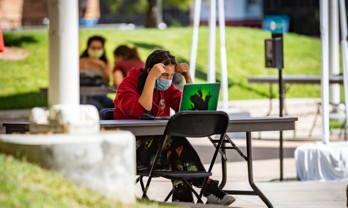 Um estudante trabalha ao ar livre em seu laptop na Universidade Chapman em Orange, Califórnia, em 14 de outubro de 2020 (John Fredricks/Epoch Times)