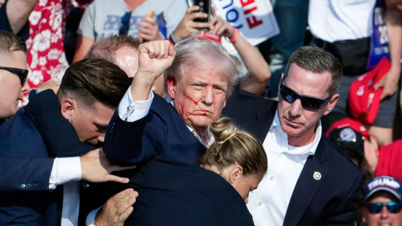 O ex-presidente Donald Trump, com sangue no rosto, é cercado por agentes do serviço secreto após ser baleado pelo suposto assassino Thomas Crooks na Butler Farm Show Inc. em Butler, Pensilvânia, em 13 de julho de 2024 (Rebecca Droke/AFP via Getty Images)
