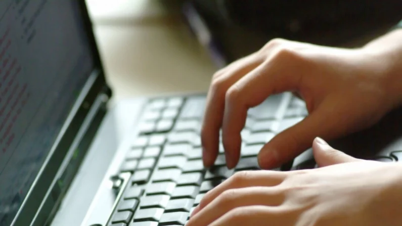 Uma pessoa digita em um teclado, em um arquivo de foto (The Epoch Times)
