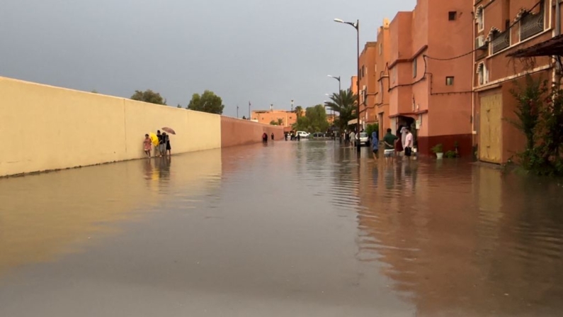 Moradores caminham em uma rua inundada na cidade de Ouarzazate, no Marrocos (Foto: ABDERAHIM ELBCIR/AFP via Getty Images)