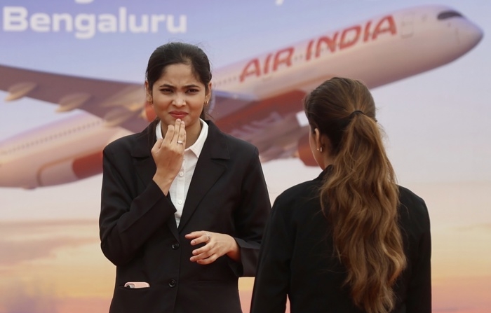  Membros da Air India em frente ao outdoor da Air India durante a cerimônia de inauguração das instalações de manutenção, reparo e revisão (MRO) da Air India no Aeroporto Internacional de Bangalore Limited (BIAL) em Bangalore, Índia, em 04 de setembro de 2024 (EFE/EPA/JAGADEESH NV)