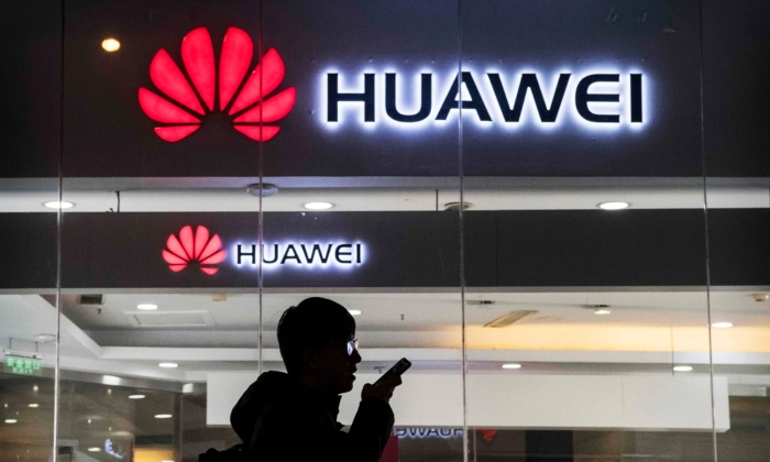 Um pedestre fala ao telefone enquanto passa por uma loja da Huawei Technologies Co. em Pequim, em 29 de janeiro de 2019. Kevin Frayer/Getty Images
