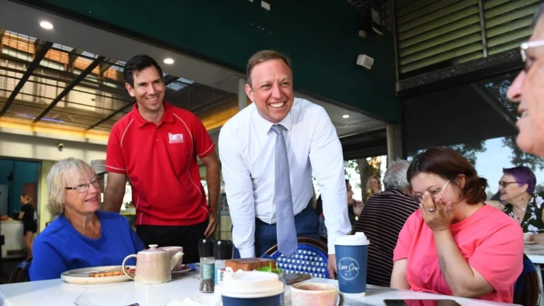 O primeiro-ministro trabalhista de Queensland, Steven Miles (segundo à direita) e o membro de Bundaberg Tom Smith (segundo à esquerda) conversam com moradores locais em um café em Bundaberg, Austrália, em 7 de outubro de 2024 (Imagem AAP/Jono Searle)
