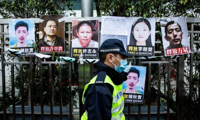 Um policial passa por cartazes de ativistas de direitos detidos colados na cerca do escritório de ligação chinês, em protesto contra a detenção em Pequim do proeminente ativista anticorrupção Xu Zhiyong, em Hong Kong, em 19 de fevereiro de 2020. Isaac Lawrence/AFP via Getty Images
