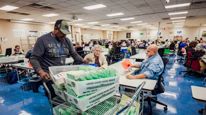 Funcionários eleitorais abrem envelopes e classificam cédulas no Centro de Tabulação e Eleição do Condado de Maricopa, em Phoenix, em 23 de outubro de 2024. (Olivier Touron/AFP via Getty Images)