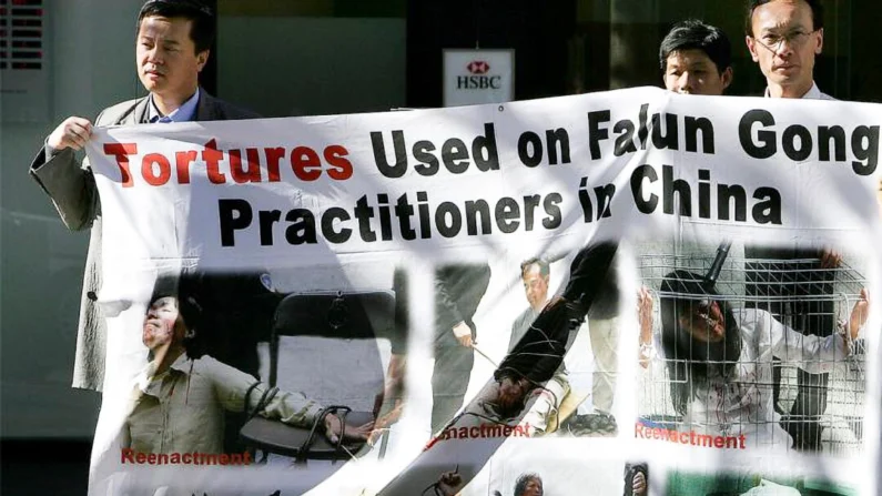 Apoiadores do Falun Gong exibem uma faixa perto de Chinatown em Sydney, em 20 de julho de 2005, mostrando encenações de tortura. (Greg Wood/AFP/Getty Images)