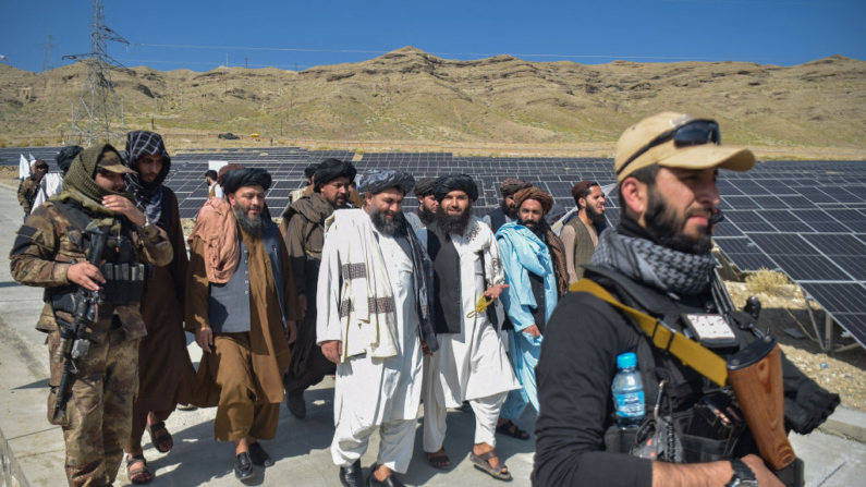 Taliban authorities walk past solar pannels after a ten megawatt solar energy project inaugurated in Naghlu in Surobi district of Kabul province on October 19, 2024. (Photo by Ahmad SAHEL ARMAN / AFP) (Photo by AHMAD SAHEL ARMAN/AFP via Getty Images)