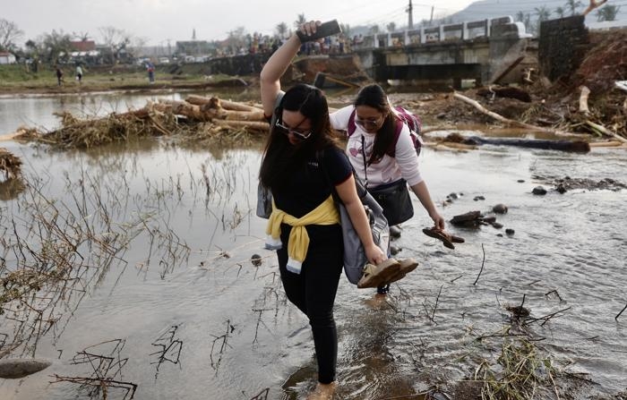 Moradores filipinos atravessam um rio próximo a uma ponte danificada afetada pelo tufão Usagi, no município costeiro de Santa Ana, província de Cagayan, Filipinas, em 15 de novembro de 2024. O tufão Usagi, o quinto grande tufão a atingir as Filipinas, trouxe mais danos após o ataque dos tufões Toraji, Trami, Yinxing e Kong-rey (EFE/EPA/FRANCIS R. MALASIG)