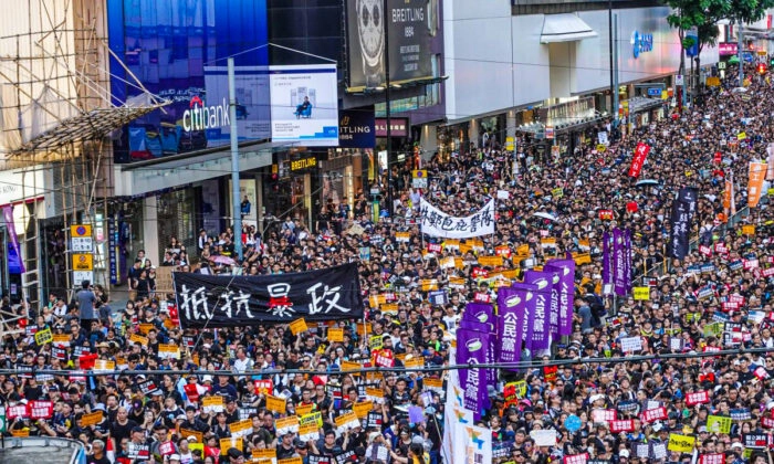 Manifestantes marcham nas ruas com uma placa que diz "Resista à tirania" durante um protesto pró-democracia em Hong Kong em 1º de julho de 2019. (Yu Gang/Epoch Times)
