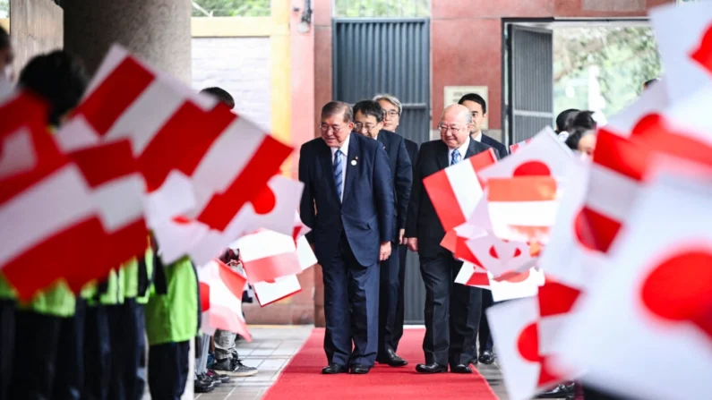 
O primeiro-ministro japonês Shigeru Ishiba (E) se curva para crianças acenando bandeiras nacionais japonesas e peruanas ao chegar para uma reunião com membros da comunidade peruana-japonesa na Associação Peruana Japonesa em Lima, Peru, em 17 de novembro de 2024. (Ernesto Benavides/AFP via Getty Images)
