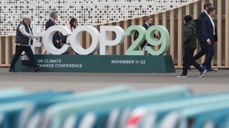 Participantes passam por uma placa da COP29 U.N. Climate Summit do lado de fora do local, em Baku, Azerbaijão, em 23 de novembro de 2024. (AP Photo/Sergei Grits)
