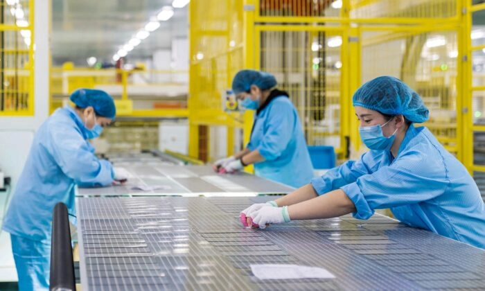 Trabalhadores fazem módulos solares fotovoltaicos usados para pequenos paineis solares em uma fábrica em Haian, na província de Jiangsu, China, em 7 de janeiro de 2022 (STR/AFP via Getty Images)
