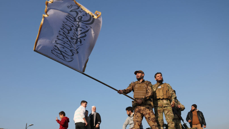 Um combatente antigoverno agita uma bandeira islâmica de cima de um tanque em Damasco em 9 de dezembro de 2024. Os sírios se reuniram na praça principal da capital, Damasco, em 9 de dezembro, para marcar o que muitos consideram como um novo amanhecer há muito esperado após a queda de Bashar al-Assad. Assad fugiu para a Rússia no dia anterior, depois que uma ofensiva relâmpago liderada por rebeldes islâmicos o expulsou do poder, abrindo um novo capítulo na história da Síria após cinco décadas de regime de seu clã (Foto de OMAR HAJ KADOUR / AFP) (Foto de OMAR HAJ KADOUR/AFP via Getty Images)
