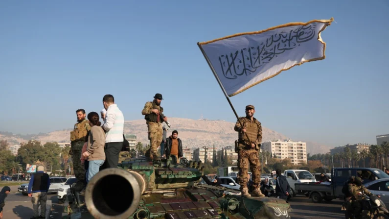 Um combatente antigovernamental acena uma bandeira islâmica do topo de um tanque em Damasco em 9 de dezembro de 2024. (Omar Haj Kadour/AFP via Getty Images)
