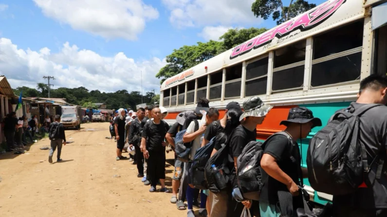 Imigrantes chineses ilegais no acampamento Canaán Membrillo embarcam em um ônibus para a próxima etapa de sua jornada até a fronteira sul dos EUA, no Panamá, em 3 de julho de 2024. (Oscar Ramirez para Epoch Times)
