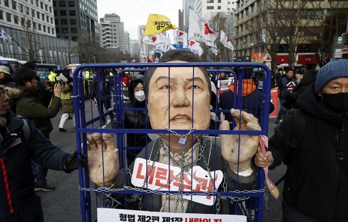 Foto de 12 de dezembro de 2024 de membros da Confederação Coreana de Sindicatos (KCTU) e grupos cívicos marchando durante uma manifestação exigindo a renúncia e a prisão do presidente sul-coreano em Seul (EFE/JEON HEON-KYUN)