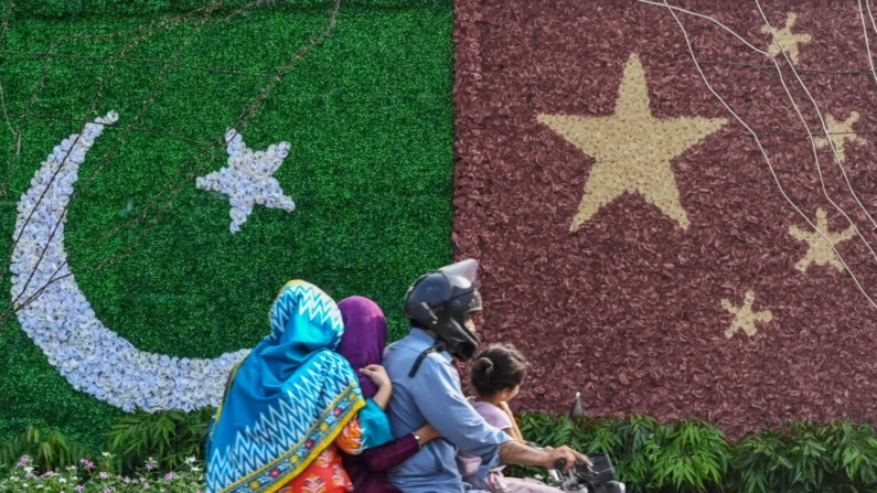 Uma família passa por uma decoração com as bandeiras da China e do Paquistão antes da visita do vice-primeiro-ministro chinês He Lifeng, em Lahore, Paquistão, em 30 de julho de 2023. (Arif Ali/AFP via Getty Images)
