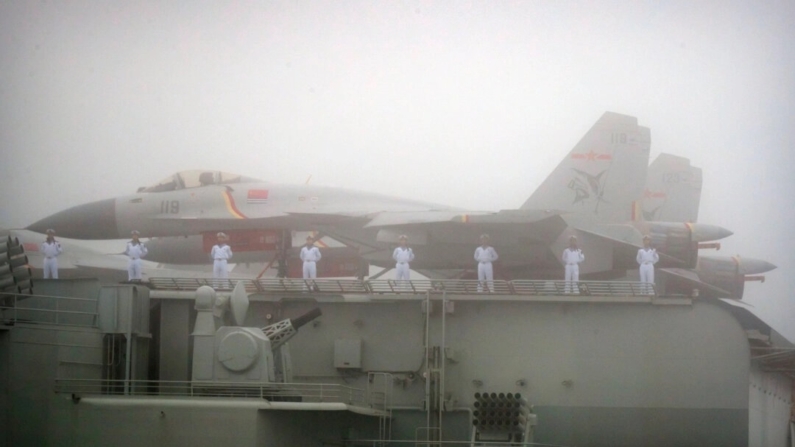 Marinheiros ficam perto de caças no convés do porta-aviões Liaoning, da Marinha do Exército de Libertação do Povo Chinês, enquanto este participa de um desfile naval para comemorar o 70º aniversário da fundação da Marinha do ELP da China no mar perto de Qingdao, na província de Shandong, leste da China, em 23 de abril de 2019. (Mark Schiefelbein/AFP via Getty Images)